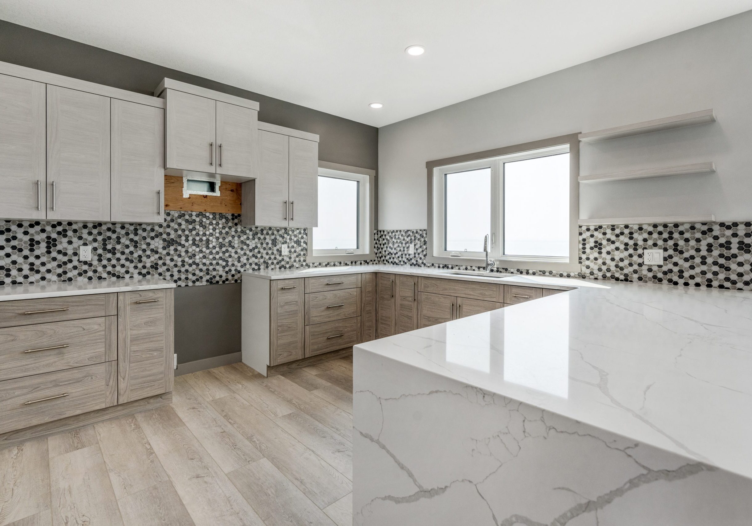 Modern kitchen with marble countertops, ample storage, and large windows.